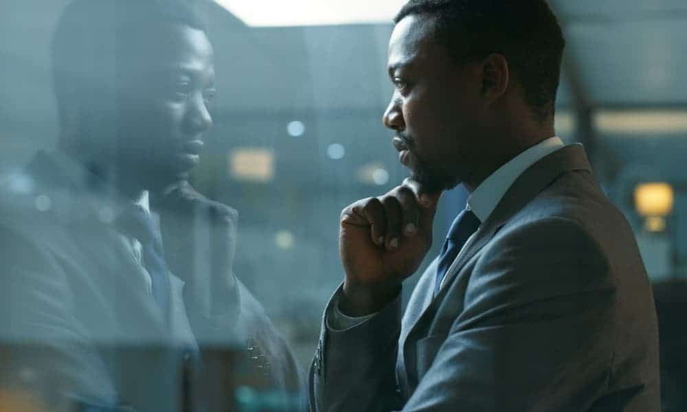 A businessman staring out of a window thinking about behavior chain analysis.